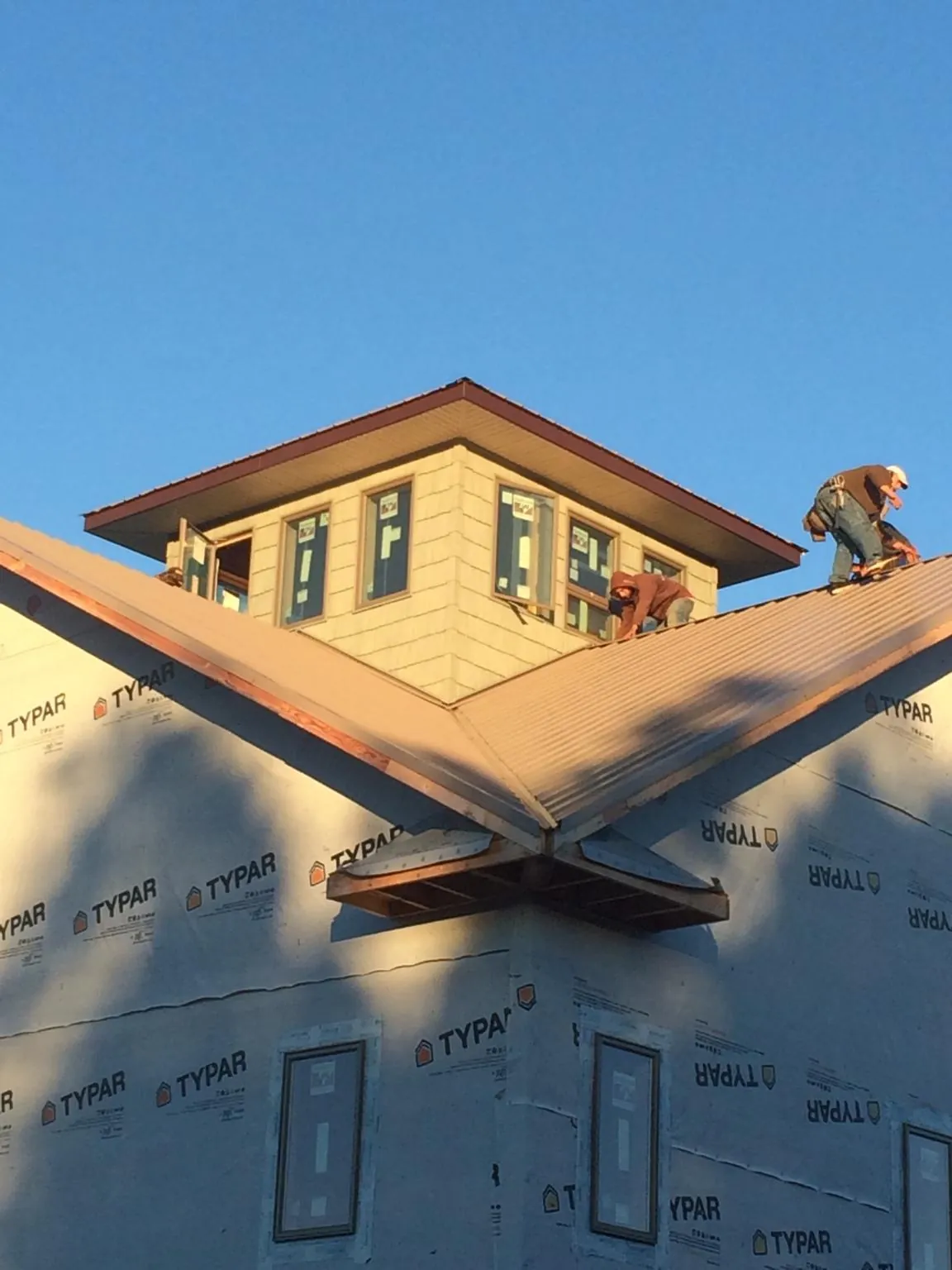 Roofers working around a rooftop cupola on a new metal roof at sunset — Roof Waterproofing in Granville by Roofing Brothers